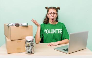 young pretty woman  looking surprised and shocked, with jaw dropped holding an object. donation...