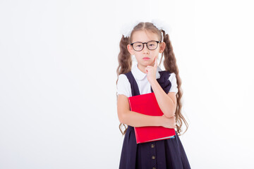 a little girl in glasses and a school uniform holds a book and a globe isolated on a white background