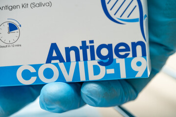 Doctor in PPE suit holding Saliva Antigen Test Kit for check Covid-19 coronavirus in hospital.