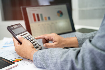 Asian accountant working and analyzing financial reports project accounting with chart graph in modern office, finance and business concept.