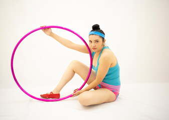 young white woman on floor with pink hula hoop, blue blouse pink shorts, red shoes, on a white background