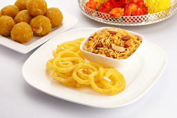 Jelebi famous Indian sweet (tradtional Indian fried sweet dessert) & Chivda or bujiya or namkin & bundi laddu with flowers in a basket
