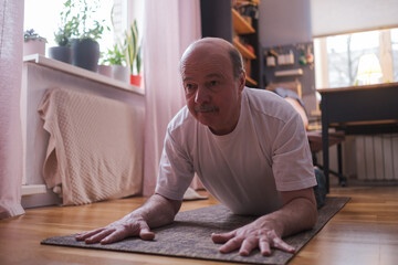Senior man doing yoga pose or pilates at home.