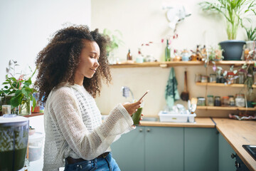 Girl browsing on social media while enjoying her green smoothie