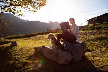 girl reading a book on a vacation day in a rural area. sunset with a background of mountains and...