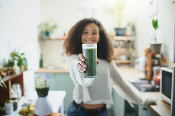 Girl showing her green smoothie at the camera