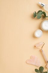 Skincare concept. Top view vertical photo of cream jars glass dropper bottle rose quartz roller gua...