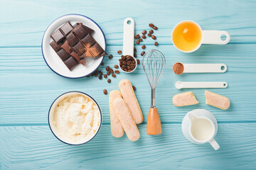 Tiramisu dessert. Ingredients for making dessert tiramisu. Cooking Italian food dessert Tiramisu with all necessary ingredients cocoa, coffee, mascarpone cheese on turquoise wooden background Top view