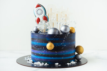 Space themed birthday cake with blue cream cheese frosting decorated with gingerbread cookies in...