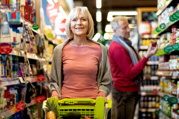 Attractive senior lady shopping with her husband at supermarket