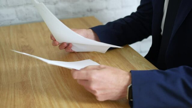 Businessman looking through a pile of job applications. The man flicks through the papers