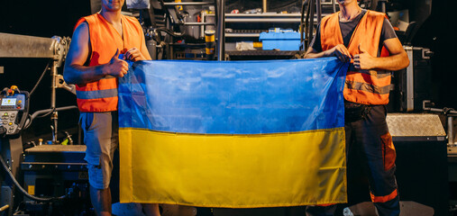 Two ukrainian young workers with Ukrainian flag in hands
