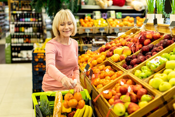 Female customer purchasing at supermarket, choosing fruits