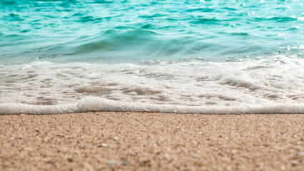 Beach sand sea water summer background. Sand beach desert texture.
White foam wave sandy seashore