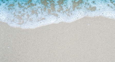 Beach sand sea water summer background. Sand beach desert texture.
White foam wave sandy seashore. top view
