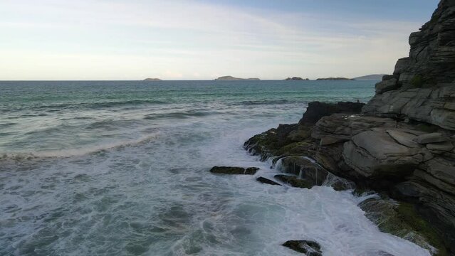 Ocean waves splashing into rocky cliff side in Geriba Beach en Buzios, Brasil