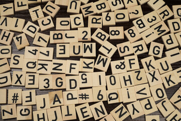 Wooden tiles with latin alphabet letters and characters on a table (brown background)