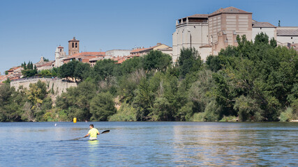 View of Tordesillas from the Duero river, in the river there is a canoe - obrazy, fototapety, plakaty