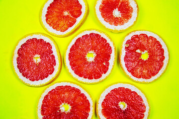 Rings of cut red Grapefruit (Latin Cītrus paradīsi) on a bright yellow background. Vegetables, fruits, healthy foods.
