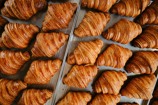 Freshly baked golden French croissants on baking sheet. Fresh classic pastries. Top view . High quality photo