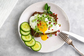 Sandwich with scrambled eggs, microgreens and pink pepper on a plate. Delicious and healthy snack