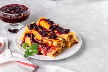 Rolled pancakes with honeysuckle jam on a plate with a mint leaf. Copy space