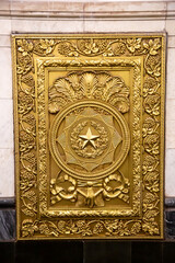 Fototapeta na wymiar The shield is rectangular in yellow bronze with drawings of grapes around the perimeter, ears and a star in the circle of the center. Architecture is applied art.