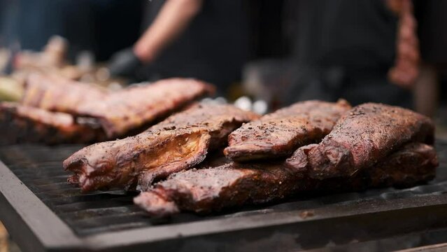 Hands of a man in black gloves rotating a barbecue on the fire
