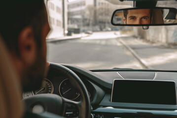 Young elegant male driving a car in the city street