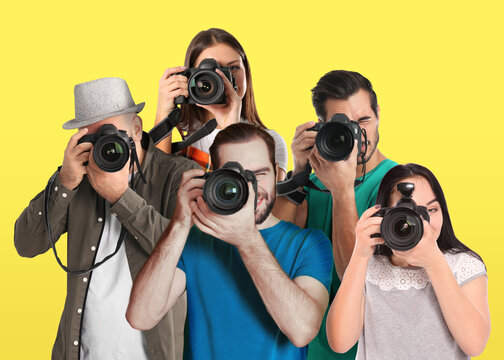 Group of professional photographers with cameras on yellow background