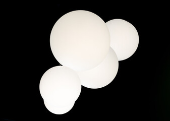 Large white ball lamps hanging from a ceiling. 