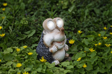 Decorative Small Solar Garden Light hedgehog, Lanterns In Flower Bed In Green Foliage. Garden Design. Solar Powered Lamps In Row