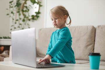 little girl uses a laptop video chat to communicate learning at home, child studying online.