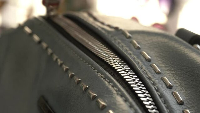 Close up of zipper of a black leather bag. Opening a bag
