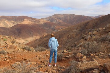 Turystka stojąca tyłem do obiektywu podziwiajaca górzysty krajobraz Fuerteventury