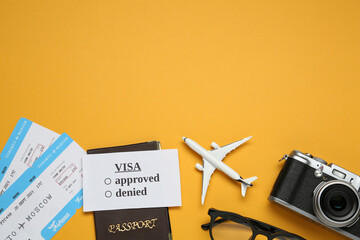 Flat lay composition with passport, toy plane and camera on orange background, space for text. Visa receiving