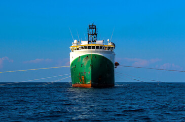 Seismic survey vessel seen from straight ahead with all towed in sea equipment deployed. Oil and...