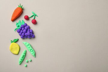 Fototapeta na wymiar Different fruits and vegetables made from play dough on light grey background, flat lay. Space for text