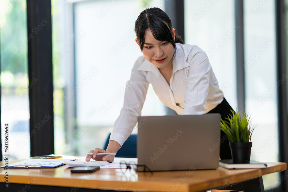 Wall mural businesswoman is using a computer laptop while standing at the working desk.