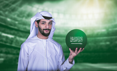 Arab man holding Saudi soccer ball standing front green stadium background.