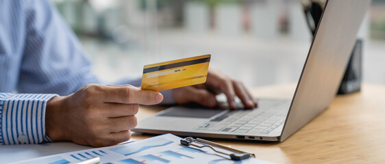 Fototapeta premium Male businessman work on computer in the office. Showing credit card. Business and lifestyle concept.