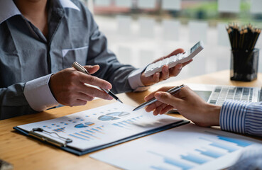 Business professionals working together at office desk, hands close up pointing out financial data on a report, teamwork concept