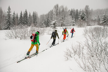 Group ot travelers, male skier tourists with backpacks hiking on skis in deep snow