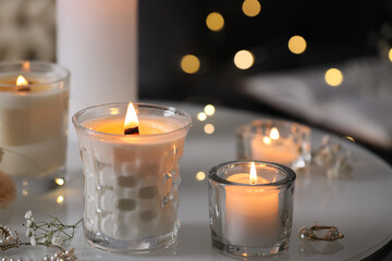 Burning candles and jewelry on table indoors
