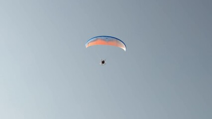 Beautiful view of flying man on hang glider against background cloudless sky. 