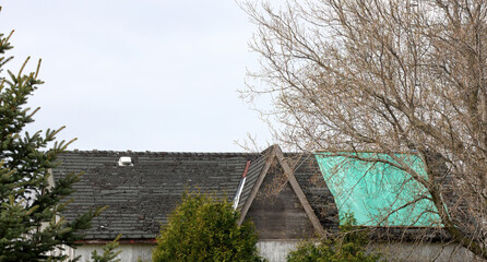 Fototapeta na wymiar Residential Roof in Desperate Need of Repair or Replacement with peeling shingles and Tarp