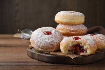 Delicious donuts with jelly and powdered sugar on wooden table