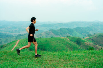Asian men who trail runners. Wearing sportswear practicing on a trail running in the mountains behind a beautiful mountain on a clear day. Practice running happily