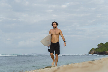 Fototapeta na wymiar Young handsome man with a surfboard on the ocean.