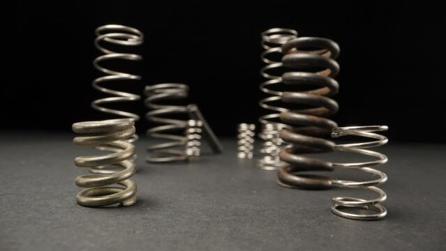 A set of metal springs are on the table, the camera flies through them. Dolly slider extreme close-up. Laowa Probe